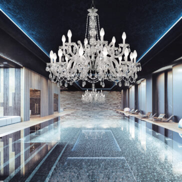 An opulent indoor pool area features an Outdoor Crystal Glass Chandelier. The pool is encircled by sleek tiles and modern lounge chairs, basking in natural light streaming through large windows. This creates a serene ambiance with outdoor-like tranquility.