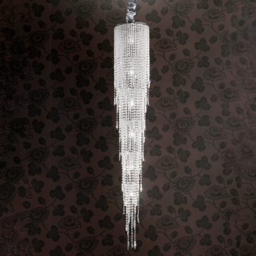 Long Tiered Crystal Italian Chandelier The Long Tiered Crystal Italian Chandelier features cascading strands and hangs against dark floral-patterned wallpaper, creating an elegant, luxurious ambience.