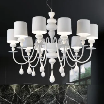 Contemporary High End White Chandelier A Contemporary High End White Italian Designer Chandelier with multiple candle-like lampshades hangs from the ceiling, featuring intricate curved arms and teardrop-shaped ornaments. The background shows a dark wall and window reflection, highlighting its luxurious allure.