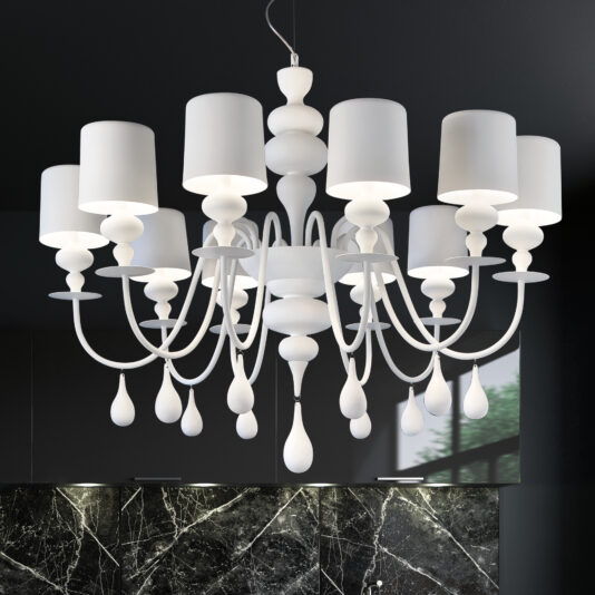 A Contemporary High End White Italian Designer Chandelier with multiple candle-like lampshades hangs from the ceiling, featuring intricate curved arms and teardrop-shaped ornaments. The background shows a dark wall and window reflection, highlighting its luxurious allure.
