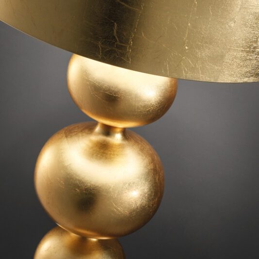 Designer Modern Gold Leaf Floor Lamp Close-up of a Designer Modern Gold Leaf Floor Lamp with a textured shade and glossy, spherical base. This stylish lamp showcases three stacked spheres for a sleek, luxurious look against a dark backdrop.