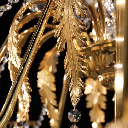 Close-up view of the Large Italian Gold Plated Crystal Chandelier featuring intricate leaf designs and hanging Swarovski crystal ornaments. The image captures the detailed craftsmanship and sparkling reflections of light from the crystals.