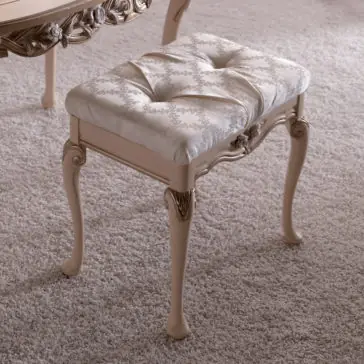 Luxurious Italian Dressing Table Stool An elegant, tufted piano bench with a padded, floral-patterned cushion. The bench showcases intricate carvings on its wooden frame and curved legs. It is placed on a plush, light-colored carpet next to the matching Luxurious Italian Dressing Table Stool.