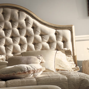 Classic Bronze Designer Button Upholstered Bed The Classic Bronze Designer Button Upholstered Bed features a padded, tufted headboard in a soft beige color, making it incredibly cozy. Adorned with multiple pillows and a quilted bedspread, the bed exudes timeless elegance with its designer button accents. The varied textures and tones of the pillows create a warm and inviting atmosphere.