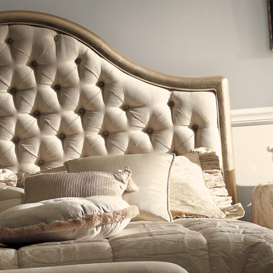 The Classic Bronze Designer Button Upholstered Bed features a padded, tufted headboard in a soft beige color, making it incredibly cozy. Adorned with multiple pillows and a quilted bedspread, the bed exudes timeless elegance with its designer button accents. The varied textures and tones of the pillows create a warm and inviting atmosphere.
