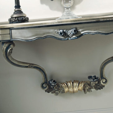 French Rose Wall Fixing Console Table A French Rose Wall Fixing Console Table with intricate details, including a carved floral design and gold accents, is elegantly attached to the wall. The table boasts elegant curved legs and serves as a platform for decorative items, such as a lamp and a glass dish.