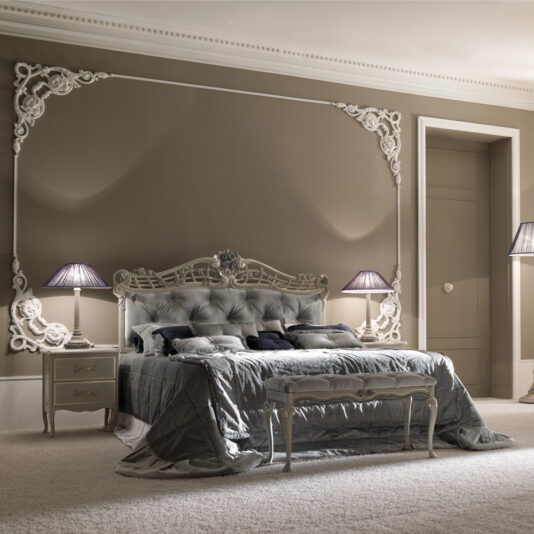 Luxurious bedroom with a Trailing Roses Italian Button Upholstered Designer Bed featuring an elegant tufted headboard and footboard. Includes plush bedding adorned with cushions, trailing roses, matching nightstands with table lamps, and intricate wall decor. The room showcases soft neutral tones and a plush carpet.