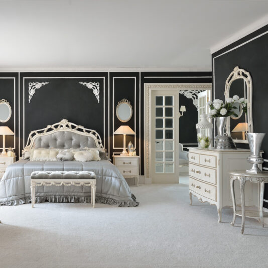 Designer High End Italian Chest of Drawers Elegant bedroom with luxurious decor, featuring a vintage bed with an ornate headboard and plush bedding, flanked by matching nightstands and lamps. The black walls with white trim add contrast, while a stylish dresser with a mirror and floral arrangement complete the look alongside the Designer High End Italian Chest of Drawers.
