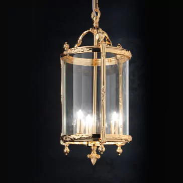 Italian Gold Lantern Ceiling Light The Italian Gold Lantern Ceiling Light chandelier boasts a lavish gold frame and transparent glass panels that elegantly display several illuminated candle-style bulbs within. Hanging from a gold chain, this exquisite fixture stands out strikingly against a dark backdrop.