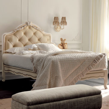 Italian Rose Detail Luxury Single Bed A bedroom scene with a plush, tufted headboard bed made with white linens and a beige quilted blanket. A teddy bear is placed on the Italian Rose Detail Luxury Single Bed. A wall-mounted dual wicker-light fixture, white curtains, and an upholstered bench at the foot of the bed complement the decor.