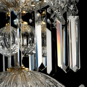 Close-up of the Ornate Italian Drop Crystal Pendant Chandelier showcasing its magnificent hanging crystal prisms reflecting light. The image highlights the intricate details of the crystals and the golden accents that suspend them, all set against a black background that enhances the clarity and sparkle of the prisms.