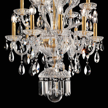 A close-up of the Ornate Italian Drop Crystal Pendant Chandelier showcasing its gold accents. The chandelier is adorned with intricate designs, teardrop-shaped crystals, and lit candle-style bulbs, creating a dazzling and elegant display against a black background.