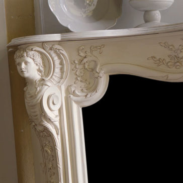 Elaborate Italian Fireplace Surround Close-up of an ornately carved white antique mirror frame. The intricate design includes floral patterns and a detailed carving of a cherub's face with wings. Reminiscent of the *Elaborate Italian Fireplace Surround*, the mirror is part of a larger piece of furniture, with porcelain dishes visible on top.