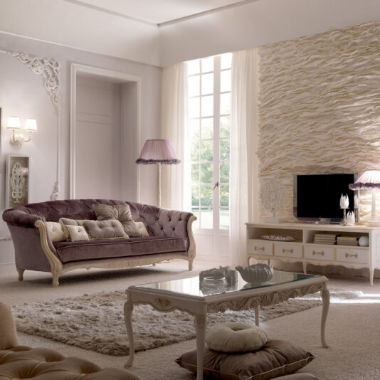 Reproduction Italian Rectangular Coffee Table A luxurious living room features a plush, purple velvet sofa adorned with multiple pillows. The Reproduction Italian Rectangular Coffee Table sits on a soft, textured rug. A large window allows natural light to fill the room, illuminating a TV on an ornate stand and elegant decor.