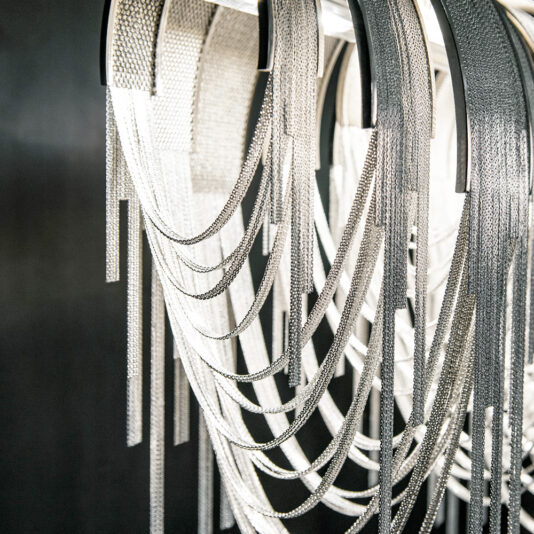 Contemporary Glamorous Rectangular Chain Chandelier The Contemporary Glamorous Rectangular Chain Chandelier features overlapping silver chains cascading in loops, creating a shimmering effect against a dark background. The elegant design resembles draped jewelry in a chandelier form.