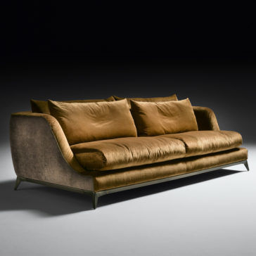 Contemporary Designer Velvet Sofa The Contemporary Designer Velvet Sofa showcases plush, golden-brown upholstery set against a dark background. It features four large, comfortable cushions and a slightly curved design with slim metal legs for support.