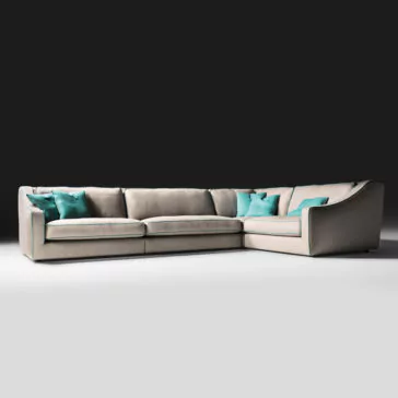 The Designer Corner Sofa, a large U-shaped beige sectional, is adorned with blue-green throw pillows and positioned against a dark background. The plush and comfortable cushions complement its sleek, modern design featuring clean lines and a slightly reclined backrest.