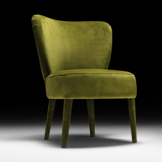 Designer Velvet Dining Chair A modern Designer Velvet Dining Chair upholstered in rich olive green velvet features a high, slightly curved backrest and sturdy wooden legs, all showcased against a dark background with a spotlight effect illuminating the chair.