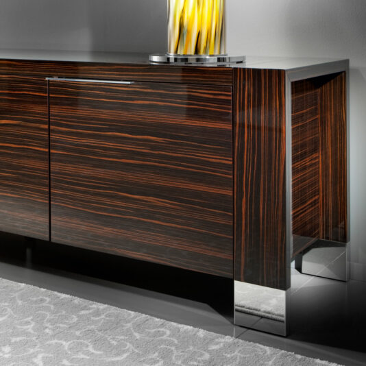 Luxury Italian Wenge Buffet The Luxury Italian Wenge Buffet, showcasing a chic wooden design with a dark, polished finish and stylish metal legs, is adorned with a yellow and white decorative glass vase on its surface. Positioned against a light-colored wall, the buffet is elegantly situated above a partially visible patterned rug.