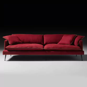 Modern Linen Designer Sofa The Modern Linen Designer Sofa, upholstered in a deep red linen, stands out against a black background with its plush cushions and elegant thin gold piping detail. The sofa's sleek, straight lines and slim black metal legs lend it a contemporary and stylish look.