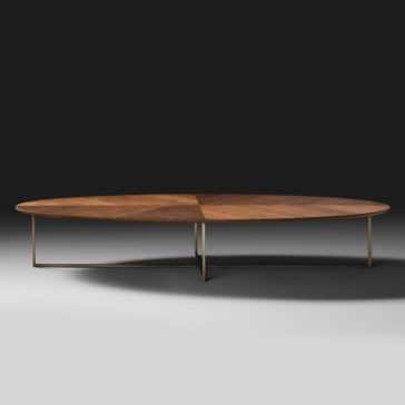 Contemporary Walnut Oval Coffee Table The Contemporary Walnut Oval Coffee Table has a wooden top with angled, triangular inlays and is supported by thin, minimalist metal legs. Set against a dark background, the sleek and modern design stands out beautifully.