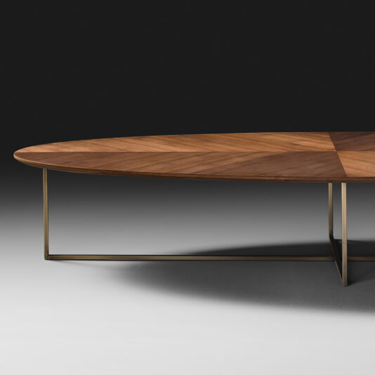 The Contemporary Walnut Oval Coffee Table boasts a dark, rich finish and features geometrically arranged wood grain. It is supported by a sleek metal base in a rectangular frame, all set against a solid black background to highlight its elegant design.