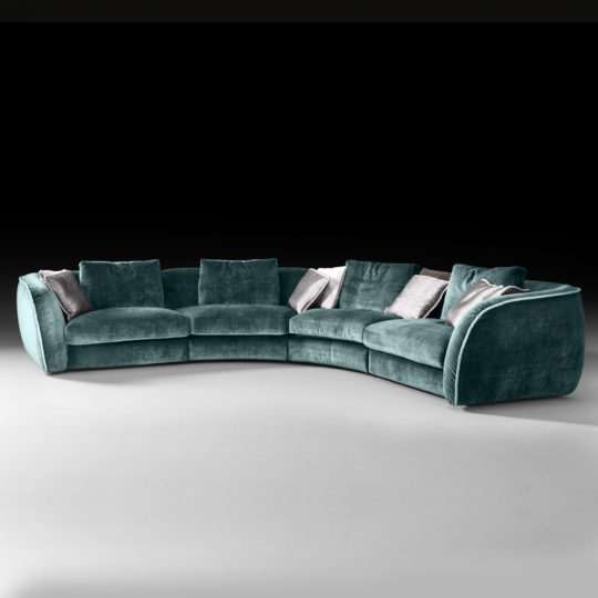 Displayed against a black background, the High End Large Velvet Modular Corner Sofa in a modern, curved design features luxurious teal velvet upholstery. It includes multiple seat cushions and backrest pillows, complemented by several grey accent pillows that add striking contrast to the stylish and plush seating arrangement.