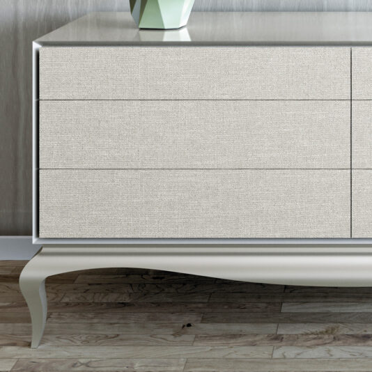 The High End Modern Linen Upholstered Drawers are a high-end dresser with a minimalist design, featuring three spacious drawers wrapped in coarse linen fabric. The dresser boasts a light grey surface and decorative tapered legs, resting on a hardwood floor, with a geometric vase adorning the top.