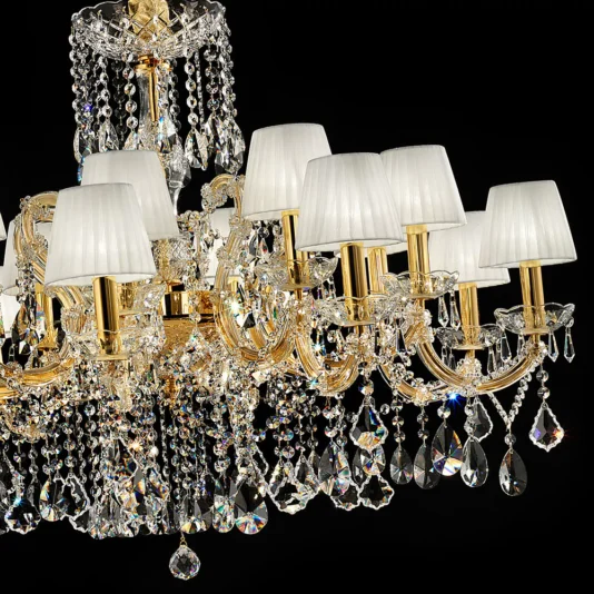 Elegant Italian Gold Plated Crystal Chandelier The Elegant Italian Gold Plated Crystal Chandelier features intricate detailing, multiple arms adorned with hanging crystal prisms, and lamps with white shades. It creates a luxurious display against a black background.