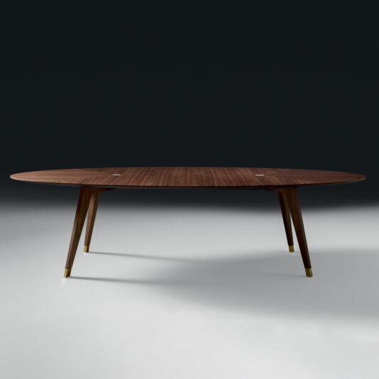 The Contemporary Oval Walnut Designer Dining Table features four angled legs with gold-colored tips, showcased against a dark background.