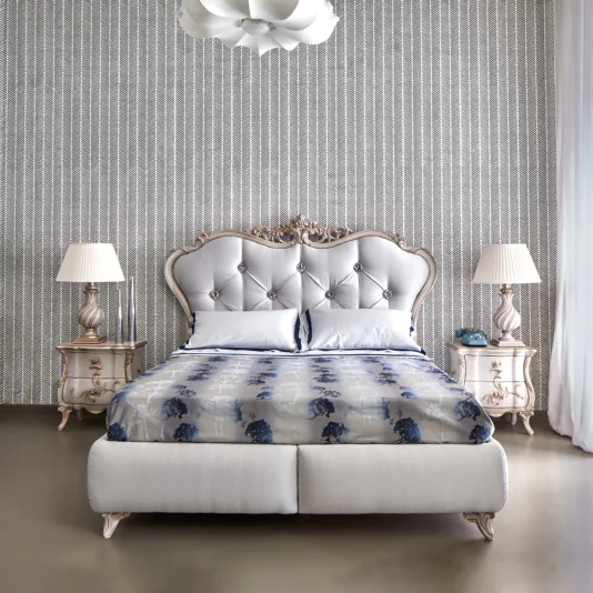 Classic Grey Italian Designer Storage Bed An elegant bedroom features a Classic Grey Italian Designer Storage Bed, paired with timeless nightstands and table lamps. The blue and white patterned bedding enhances the subtle geometric wall design, while a white pendant light elegantly hangs from the ceiling.