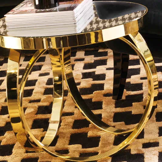 High End Italian Brass Ring Side Table The room's elegance is accentuated by a High End Italian Brass Ring Side Table with a sleek glass top on gold looped metal legs, holding magazines. The beige and black geometric-patterned rug beneath provides striking contrast.