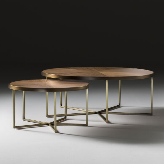 A pair of nested Contemporary Walnut Designer Coffee Tables, featuring round walnut tops and sleek angular gold metal frames, are set against a dark backdrop. The larger table is placed behind the smaller one with a slight overlap, accentuating their geometric design and modern aesthetic.