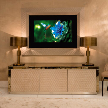 Luxury High End Wall Mounted TV and Media Unit Set The Luxury High End Wall Mounted TV and Media Unit Set showcases a blue flower and hummingbird, elegantly framed by a decorative border. A quilted-front media unit stands below, flanked by two gold lamps, completing the sophisticated modern design with warm brown tones.