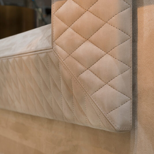 Luxury High End Wall Mounted TV and Media Unit Set Close-up of a beige quilted leather piece with diamond stitching, highlighting textured aesthetics and visible corners and seams, exemplifies the craftsmanship of the Luxury High End Wall Mounted TV and Media Unit Set.