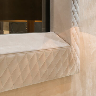 Luxury High End Wall Mounted TV and Media Unit Set Close-up of a quilted, diamond-patterned beige fabric panel at an angle. This luxury piece is part of the Luxury High End Wall Mounted TV and Media Unit Set, with soft shadows that enhance its texture and design, perfect for complementing your decor.