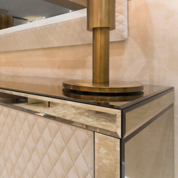 Luxury High End Wall Mounted TV and Media Unit Set The modern interior design showcases a quilted beige wall panel, glass-topped console, and brass lamp with a cylindrical base. These elegant textures and metallic finishes pair beautifully with the Luxury High End Wall Mounted TV and Media Unit Set for a luxurious contemporary look.