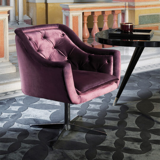 The Italian Button Upholstered Velvet Dining Chair, featuring plush purple velvet and tufted details, sits on a patterned carpet beside a round black table in an elegant room with colorful, ornate walls and columns.