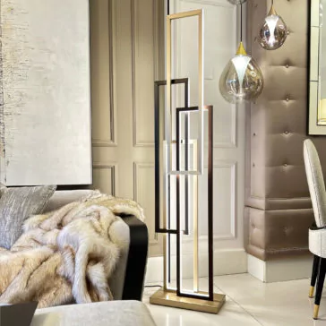 Italian Geometric Designer Modern Floor Lamp An Italian Geometric Designer Modern Floor Lamp with rectangular frames emitting light stands in a stylish living room. The room features a beige upholstered wall, metallic globe pendant lights, a cozy fur throw on a sofa, and abstract wall art.