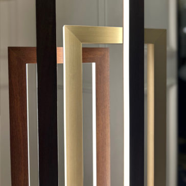 Modern Italian Geometric Designer Table Lamp A close-up view of several picture frames in various colors and finishes, including dark brown wood, light brown wood, and metallic gold. The frames are arranged at different angles next to a Modern Italian Geometric Designer Table Lamp, all standing upright against a blurred background.