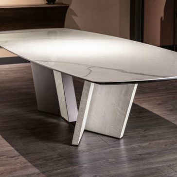 The Contemporary Rectangular Calacatta Dining Table boasts a large, glossy white Calacatta marble top with subtle grey veining, supported by two geometric, angular pedestals made of light-colored wood. Its modern aesthetic is highlighted beautifully against a dark wooden floor in any room.