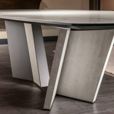 The Contemporary Rectangular Calacatta Dining Table features a sleek, flat top with distinctive V-shaped, angled supports, embodying a modern and contemporary aesthetic. Its smooth surfaces and minimalistic design make it a perfect fit on dark wooden flooring.