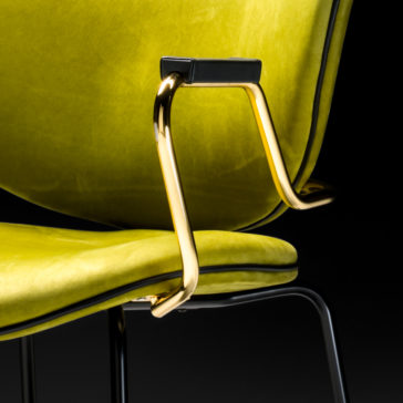 Close-up of the High End Designer Retro Style Carver Dining Chair in a vibrant lime-green color, featuring sleek gold metal armrests and thin black legs. The chair's smooth, velvety upholstery is accentuated against a solid black background, highlighting its modern retro-style design.