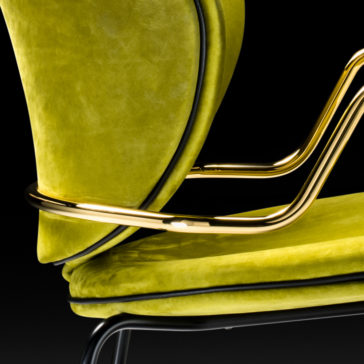 Close-up of the High-End Designer Retro Style Carver Dining Chair, showcasing its bright green velvety upholstery and sleek gold metal armrests and supports. The retro style design features sharp, clean lines and a visually striking combination of colors and textures. The black background highlights the chair's vibrant details.