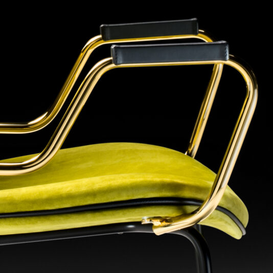 A close-up view of the High End Designer Retro Style Carver Dining Chair showcases its bright yellow-green cushioned seat, minimalist black armrests, and sleek gold metallic frames. The solid black background accentuates its modern and stylish design.