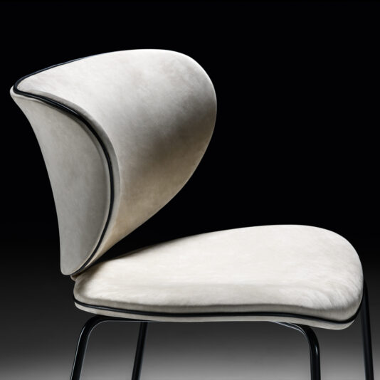 The High End Designer Retro Style Dining Chair is a high-end, modern piece featuring a sleek, curved design with light gray upholstery. Its abstract, petal-like backrest and seat are elegantly supported by slim, black metal legs. The black backdrop enhances its contemporary appeal while subtly nodding to retro style.