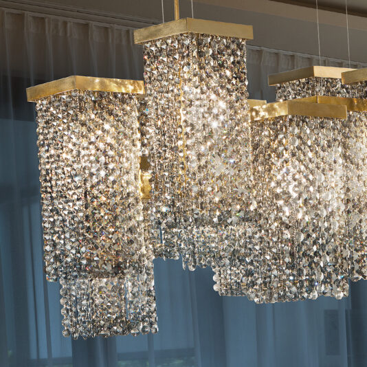 Italian Smoky Crystal Brass Contemporary Chandelier The **Italian Smoky Crystal Brass Contemporary Chandelier** exudes luxury with its multiple rectangular tiers, each adorned with sparkling smoky crystal beads from Italy and accented with brass elements. When hung against sheer white curtains, the chandelier's crystals catch the light, creating a mesmerizing shimmering effect.