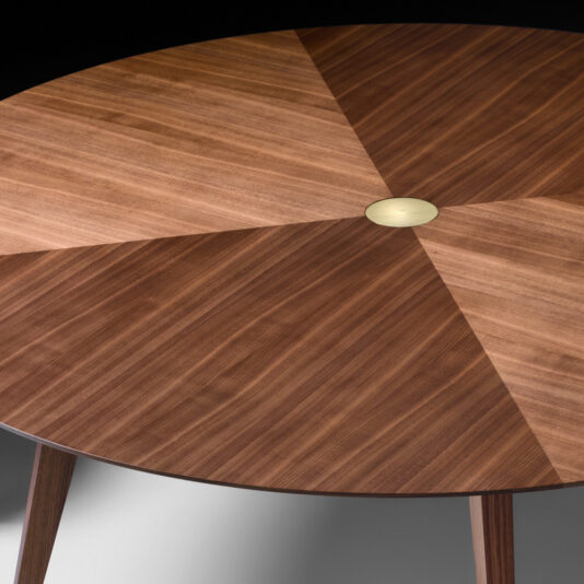 Contemporary Round Walnut Designer Dining Table Here's a close-up of the Contemporary Round Walnut Designer Dining Table, showcasing its geometric patterned veneer design in alternating shades of brown, which creates a striking starburst effect. The center of the table is adorned with a small, circular metallic insert.