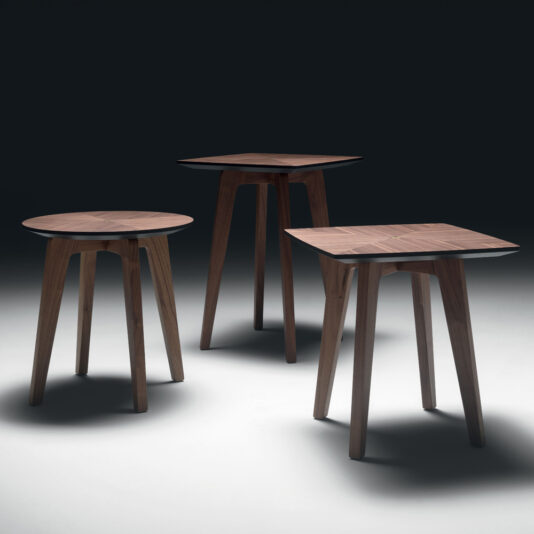 Three Contemporary Walnut Designer Side Tables of varying heights are displayed against a dark background. Two tables have square tops with rounded edges, while the third table has a round top. All tables feature tapered legs that angle slightly outward. The lighting casts soft shadows below.