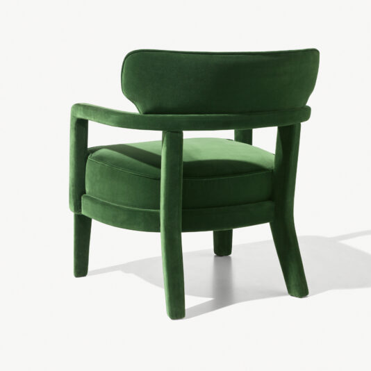 Contemporary Small Velvet Armchair The Contemporary Small Velvet Armchair is a sophisticated piece with a green upholstered seat, complemented by a curved backrest and sleek armrests. It boasts a plush cushioned seat and four sturdy legs, all enveloped in the same luxurious green fabric, making it an elegant addition to modern interiors. The background is white.